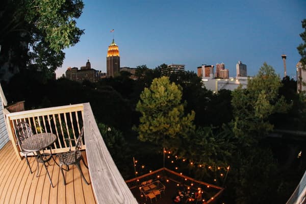 View from a balcony overlooking trees and a city skyline at dusk, with the Empire State Building illuminated.