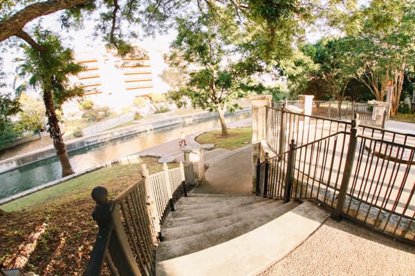 A scenic staircase leading down to a tranquil waterway surrounded by greenery.