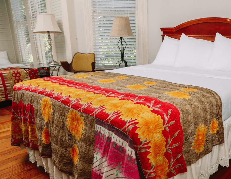 Cozy bedroom featuring a bed with a colorful floral blanket and two lamps.
