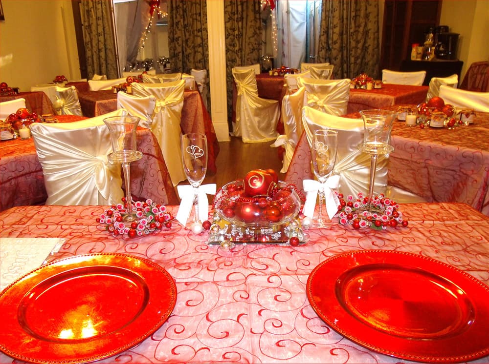A beautifully decorated dining area with red-themed table settings and elegant centerpieces.