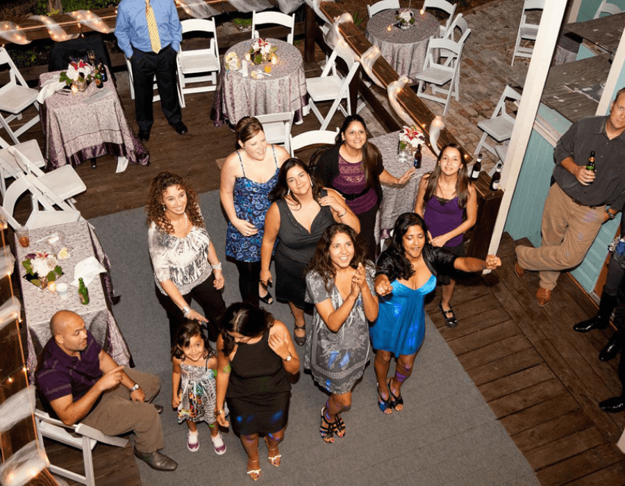 A gathered group of women and children celebrate at a festive outdoor event, surrounded by tables and decorations.