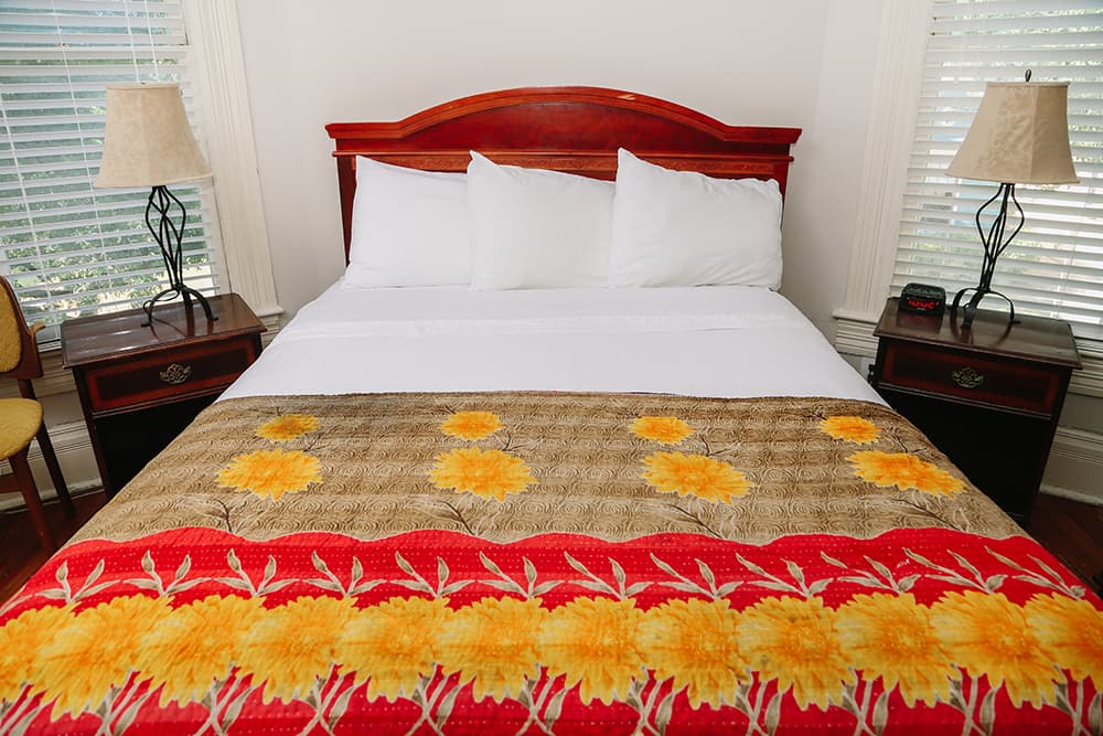 A neatly made bed with white pillows and a colorful floral blanket in a cozy room.