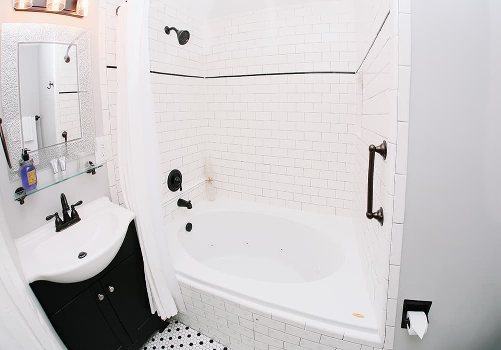 A small bathroom featuring a shower and tub, a sink with dark cabinetry, and tiled walls.