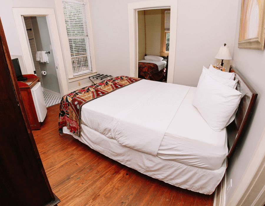 A cozy bedroom with a double bed, wooden flooring, and an adjoining bathroom.
