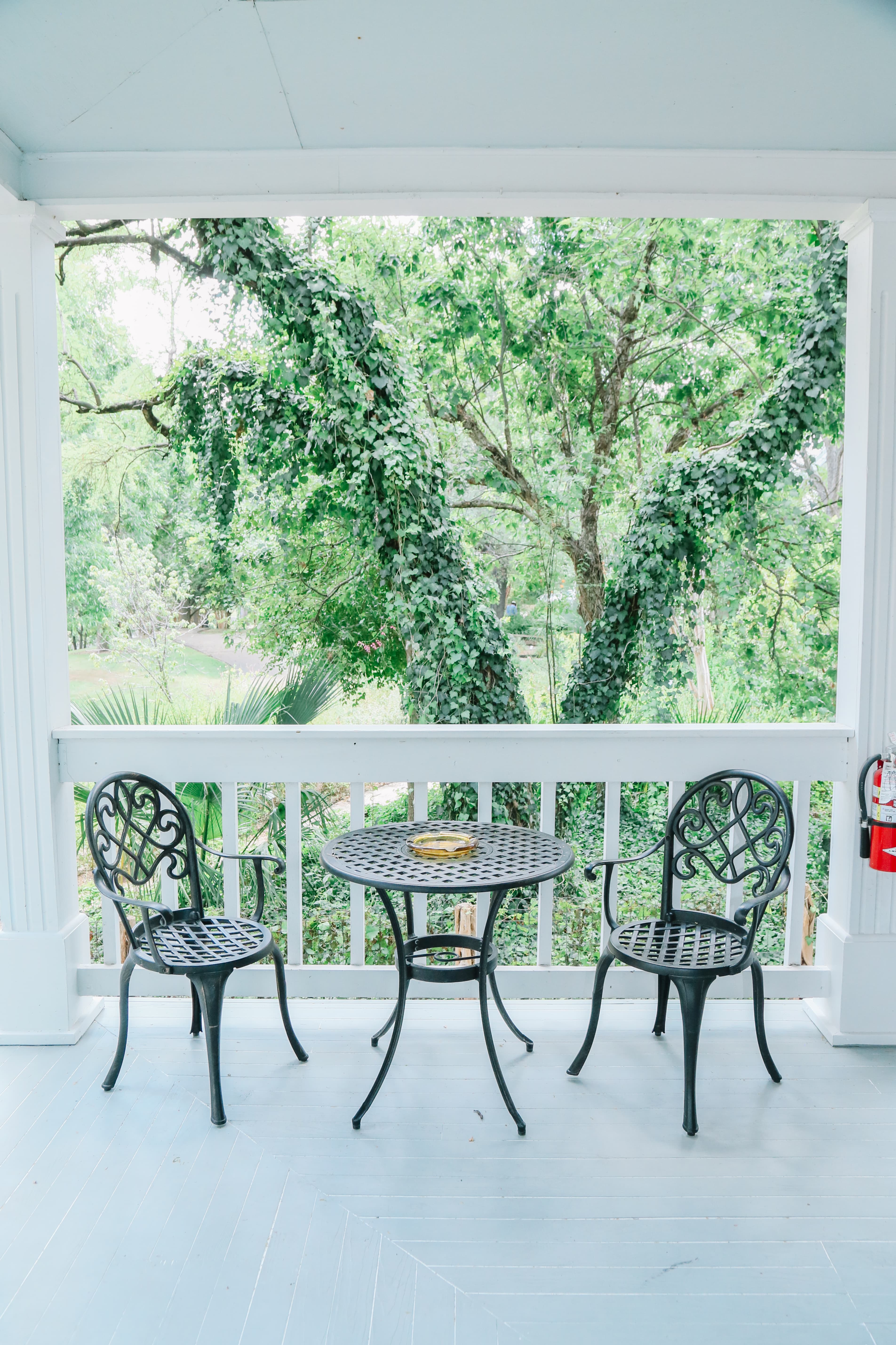 A small patio features a bistro table and two chairs, with lush greenery visible beyond.