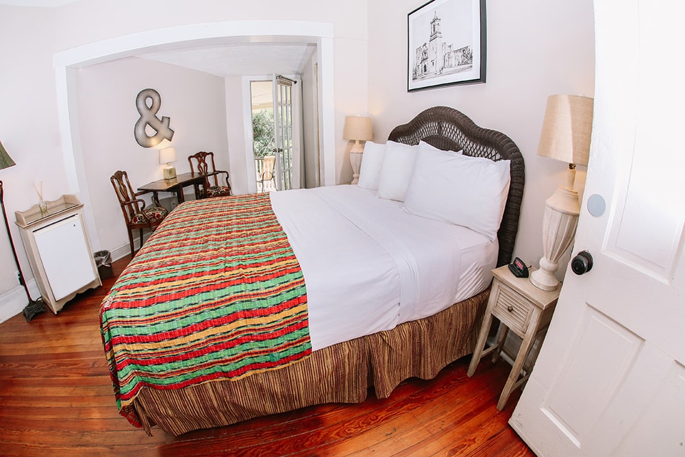 A cozy bedroom featuring a double bed adorned with a colorful striped blanket and vintage furniture.
