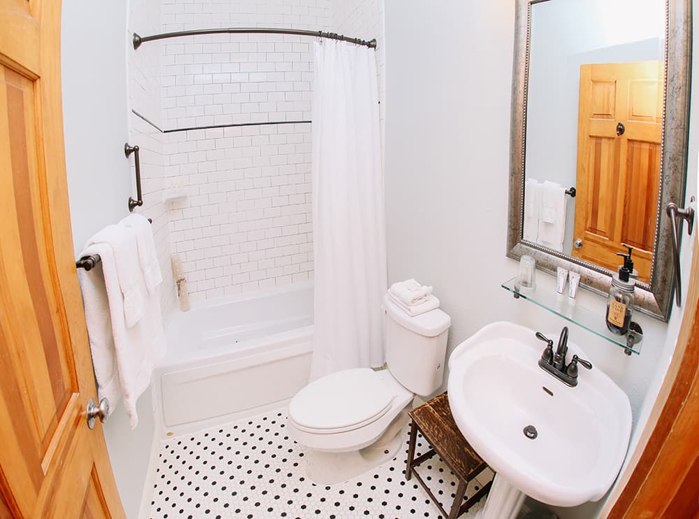 A compact bathroom featuring a bathtub, toilet, and sink with modern fixtures and a mirror.