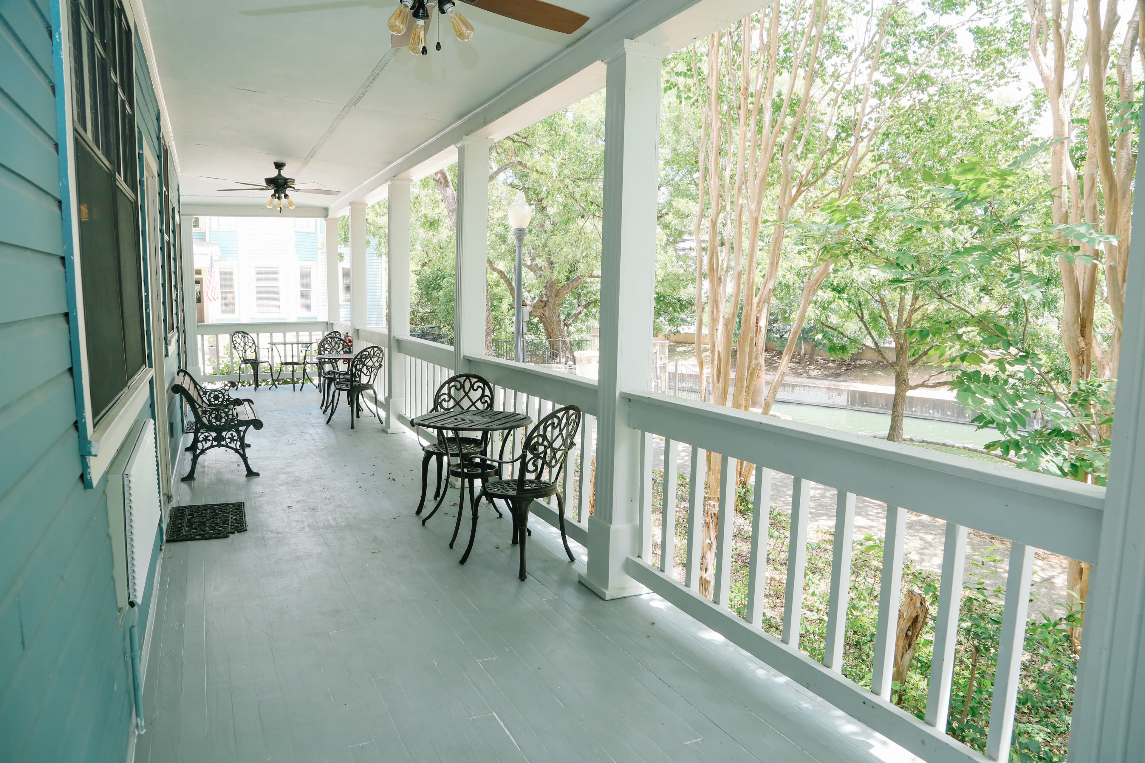 A spacious porch with metal chairs and tables overlooking greenery.