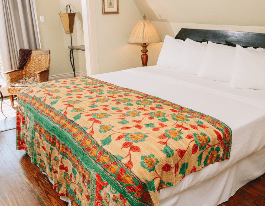 A neatly made bed with a colorful, floral-patterned blanket and white pillows in a cozy room.