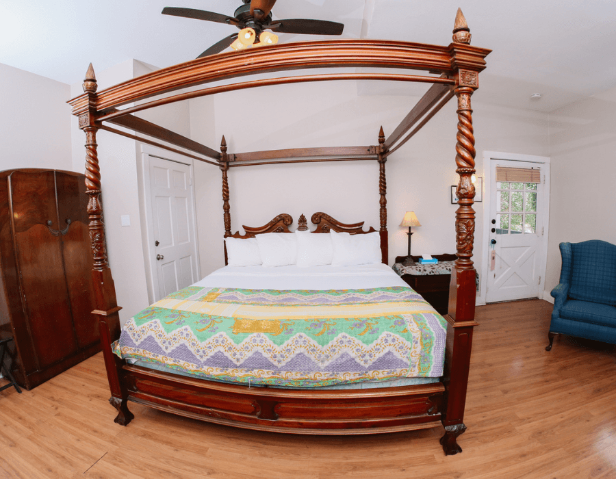 A cozy bedroom featuring a four-poster bed with colorful bedding and wooden furniture.