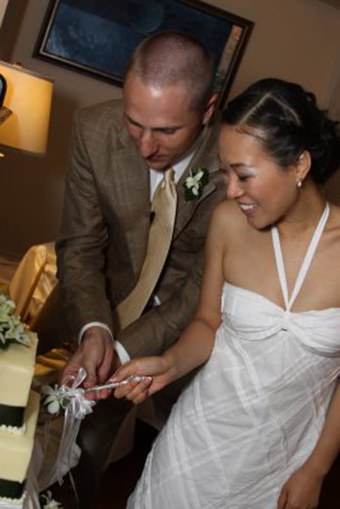 A bride and groom joyfully prepare to cut their wedding cake together.
