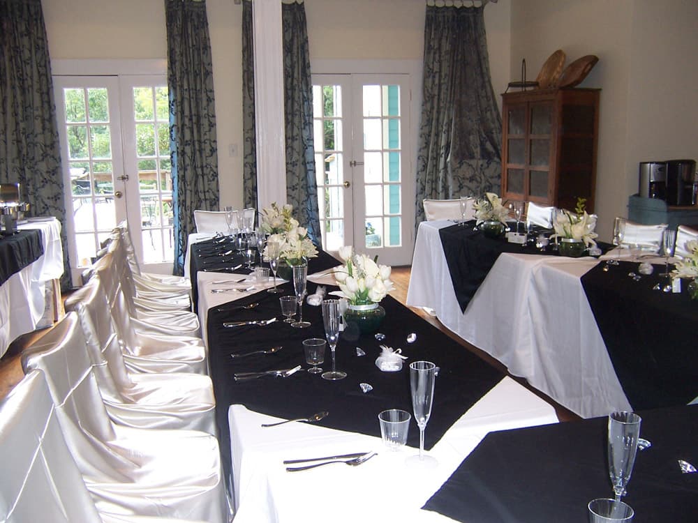 A dining area set with black and white table linens, elegant tableware, and floral centerpieces.