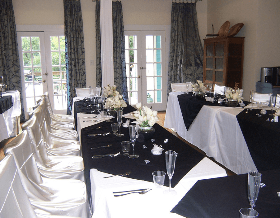 A dining room set for an elegant event, featuring black and white table settings with floral arrangements.