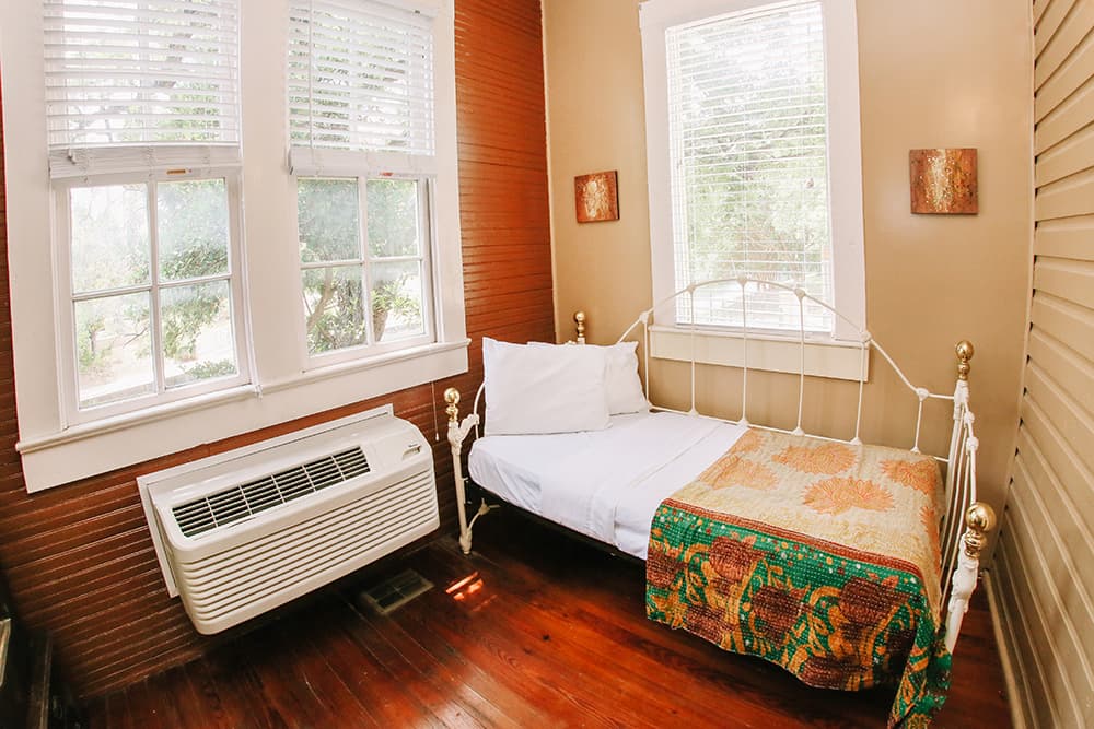 Cozy bedroom featuring a metal bed, colorful quilt, and large windows.