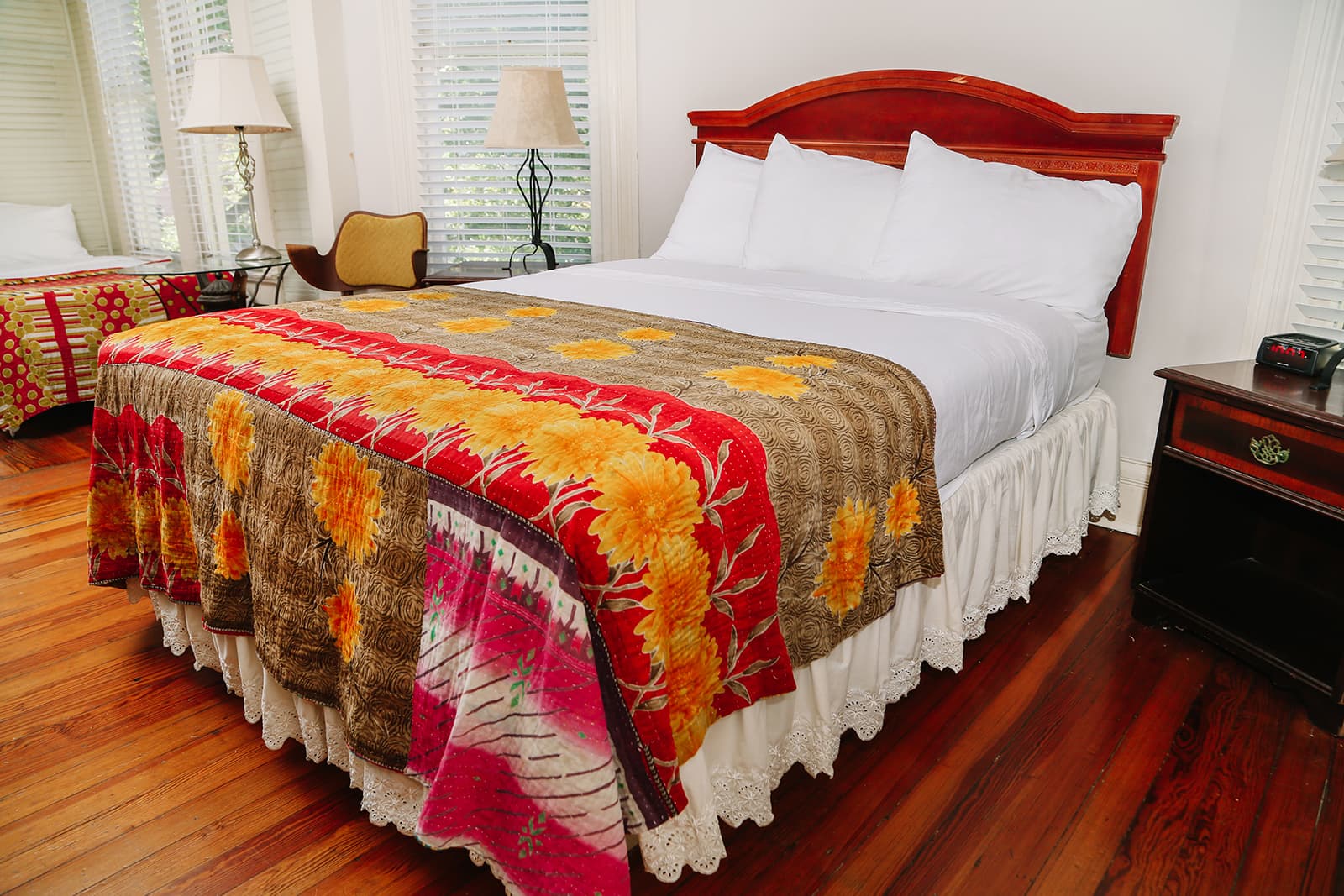 A cozy bedroom featuring a queen-sized bed with a colorful quilt and a wooden headboard.