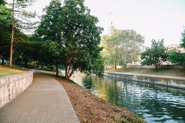 A serene path lined with trees along a calm canal.